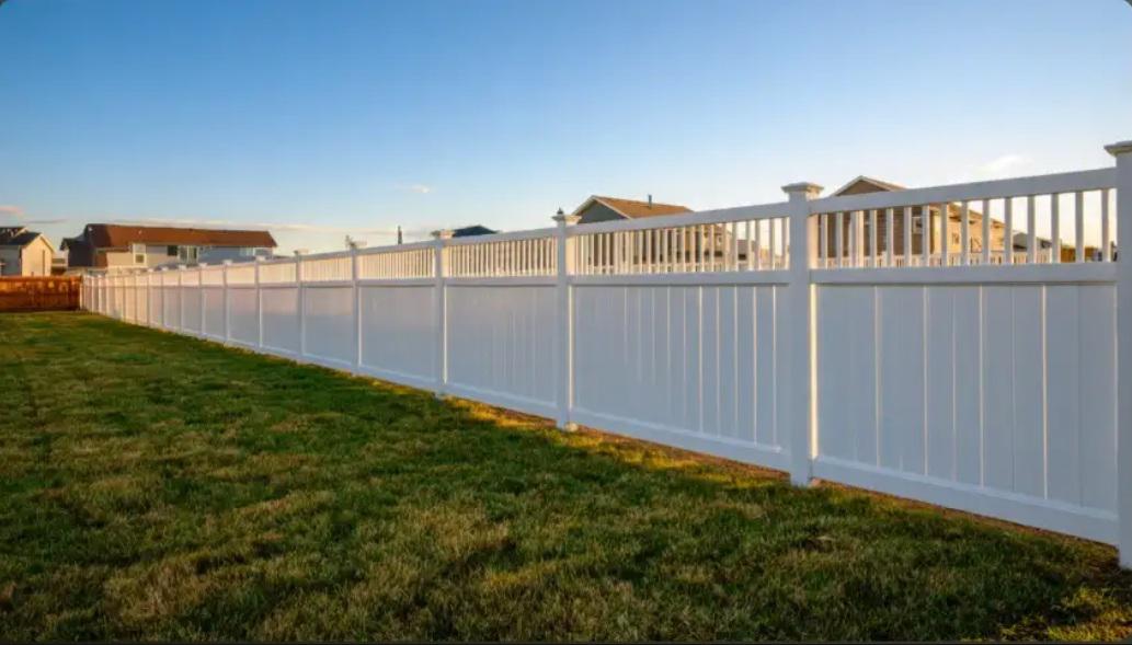 White vinyl privacy fence with lattice top in suburban backyard at golden hour